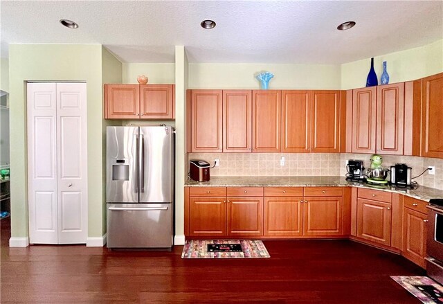 kitchen featuring decorative backsplash, stainless steel appliances, light stone counters, and dark hardwood / wood-style floors