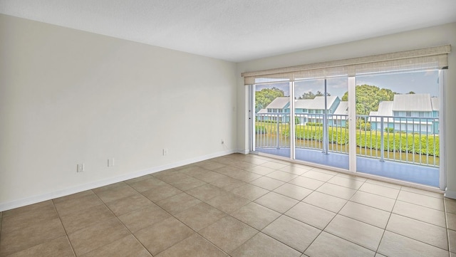 tiled empty room featuring a textured ceiling