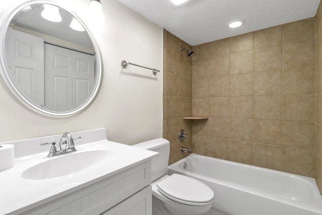 full bathroom with vanity, a textured ceiling, toilet, and tiled shower / bath combo