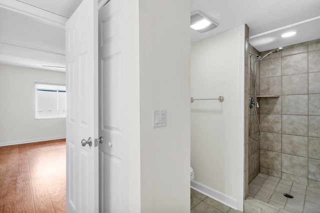 bathroom with hardwood / wood-style floors, toilet, and tiled shower