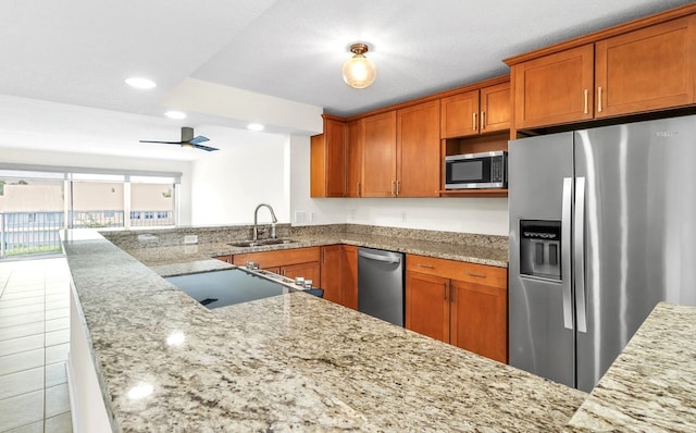 kitchen with stainless steel appliances, sink, kitchen peninsula, light stone countertops, and ceiling fan