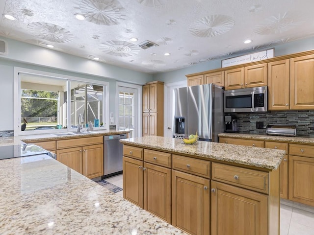 kitchen with tasteful backsplash, visible vents, appliances with stainless steel finishes, a sink, and light stone countertops