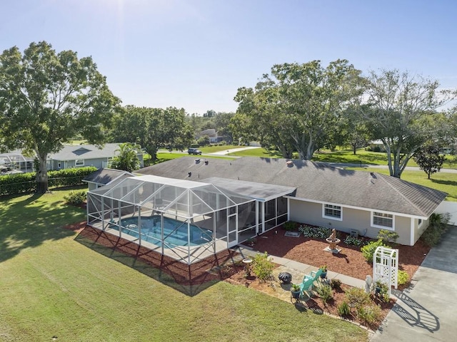 outdoor pool with glass enclosure, a lawn, and a patio area