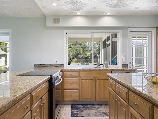 kitchen with light stone counters, a sink, visible vents, stainless steel electric range, and a wealth of natural light