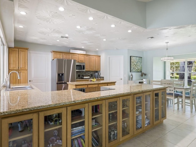 kitchen with glass insert cabinets, decorative light fixtures, a sink, and appliances with stainless steel finishes