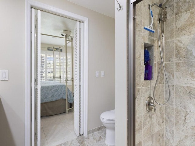 ensuite bathroom featuring toilet, connected bathroom, a shower stall, ceiling fan, and baseboards