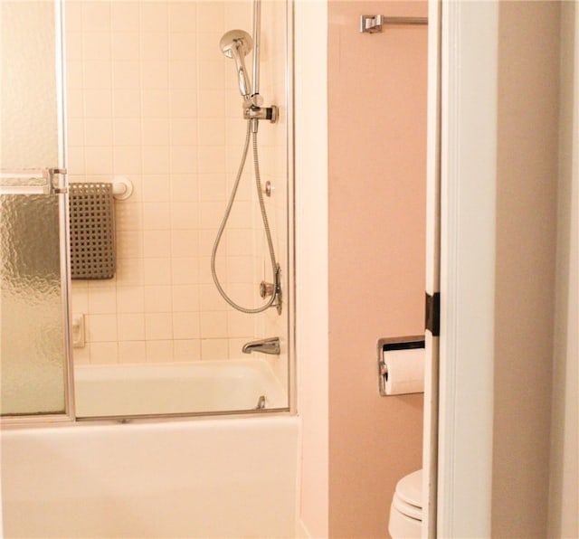 bathroom featuring combined bath / shower with glass door and toilet