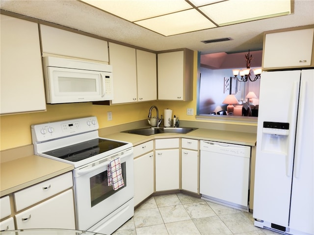 kitchen featuring white appliances, sink, pendant lighting, a chandelier, and white cabinetry