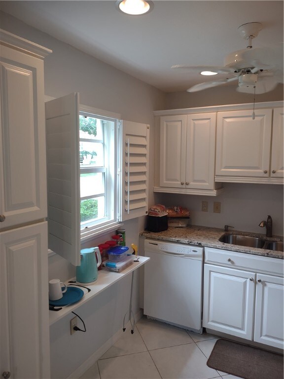 kitchen with light tile patterned flooring, white cabinetry, sink, light stone counters, and dishwasher