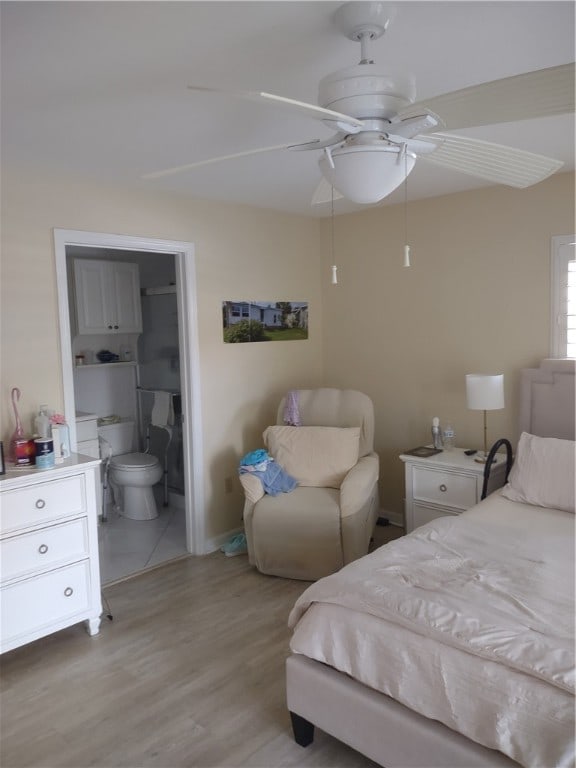 bedroom featuring light hardwood / wood-style floors, ceiling fan, and ensuite bath