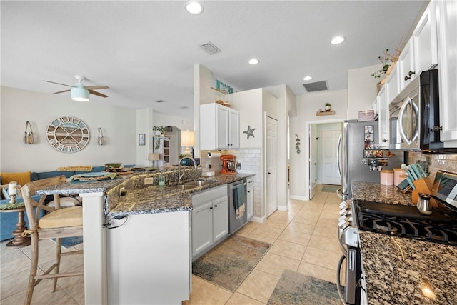 kitchen featuring ceiling fan, kitchen peninsula, decorative backsplash, white cabinetry, and stainless steel appliances