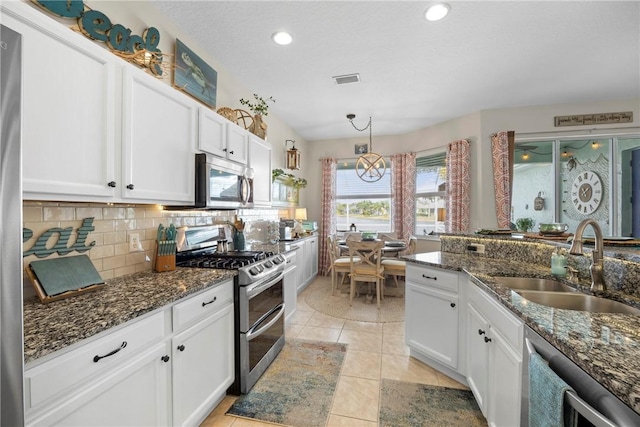 kitchen featuring sink, white cabinets, stainless steel appliances, and dark stone counters