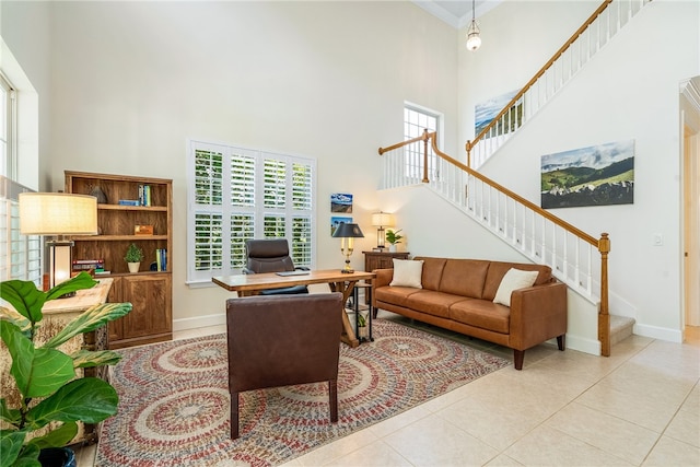 living room featuring a towering ceiling, light tile patterned flooring, and crown molding