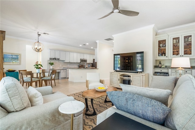 living room with light tile patterned flooring, ornamental molding, and ceiling fan with notable chandelier