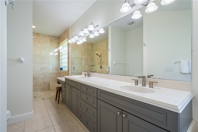 bathroom featuring vanity, tile patterned flooring, toilet, and a tile shower