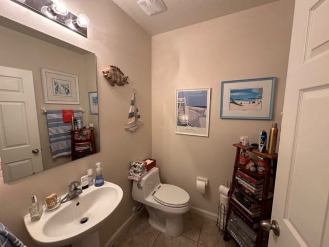 bathroom featuring toilet, sink, tile patterned floors, and a textured ceiling