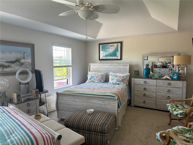 carpeted bedroom featuring ceiling fan, a textured ceiling, and a tray ceiling