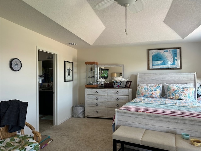 bedroom with a textured ceiling, carpet, ceiling fan, a closet, and a walk in closet