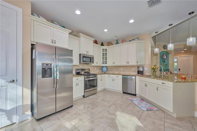 kitchen featuring kitchen peninsula, light stone countertops, backsplash, stainless steel appliances, and pendant lighting