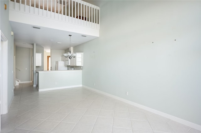 unfurnished room with a chandelier, a high ceiling, and light tile patterned floors