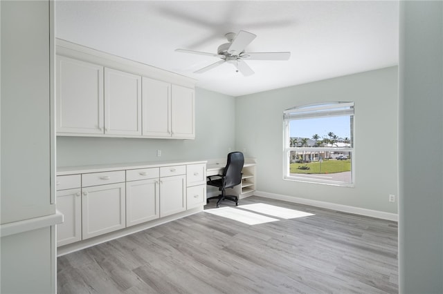 unfurnished office featuring light wood-type flooring, built in desk, and ceiling fan