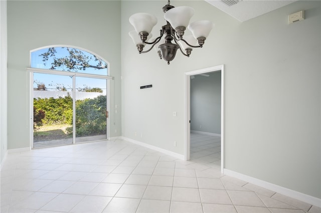 unfurnished room with a towering ceiling, light tile patterned floors, a chandelier, and plenty of natural light