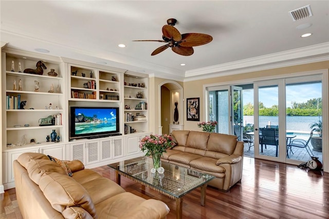 living room with wood-type flooring, built in features, ceiling fan, and ornamental molding