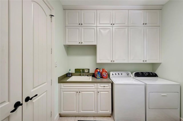 clothes washing area featuring washer and dryer, sink, light tile patterned floors, and cabinets