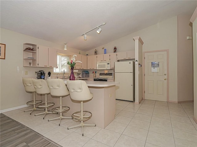 kitchen featuring open shelves, light countertops, vaulted ceiling, white appliances, and a peninsula