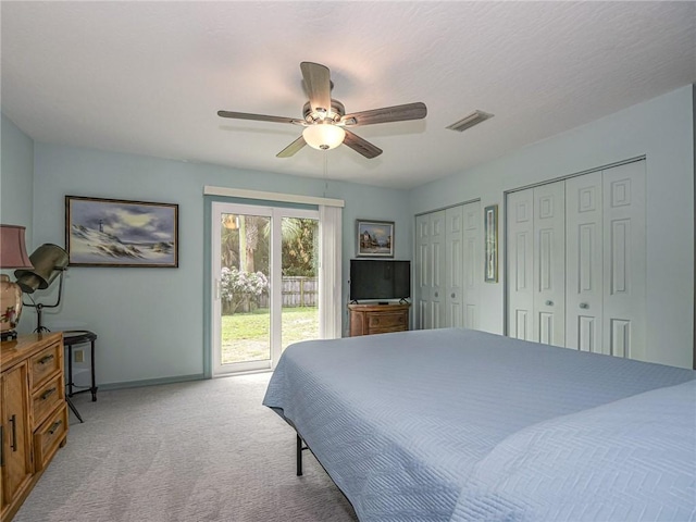 bedroom featuring light colored carpet, a ceiling fan, visible vents, multiple closets, and access to outside