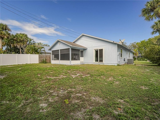 rear view of house featuring a yard, fence, a sunroom, and central air condition unit