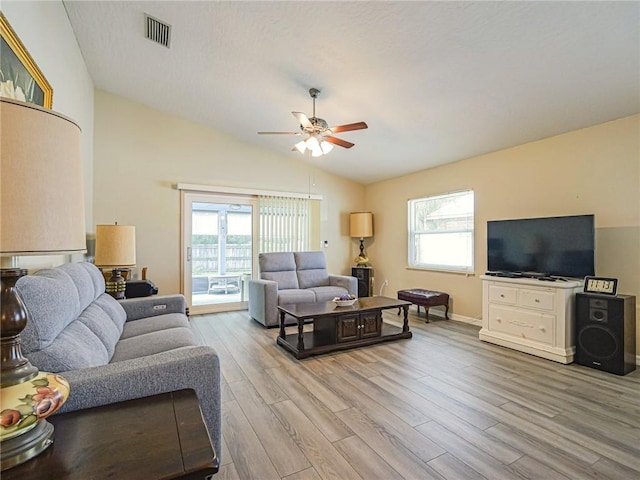 living area featuring vaulted ceiling, light wood finished floors, visible vents, and a ceiling fan