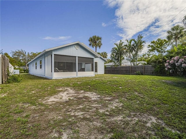 back of house with a yard, a fenced backyard, and a sunroom