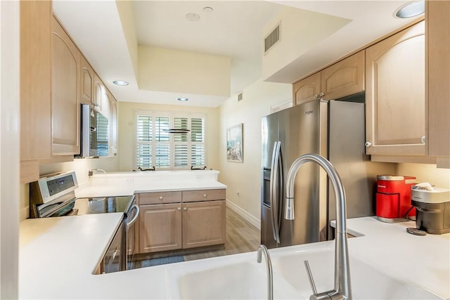 1510 Oak Harbor Blvd Unit 102, Vero Beach, FL 32967 - kitchen featuring stainless steel appliances, light brown cabinets, light countertops, a peninsula, and recessed lighting