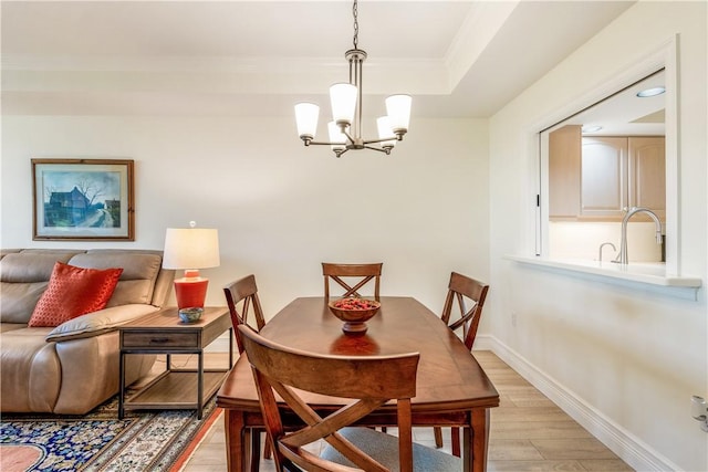 1510 Oak Harbor Blvd Unit 102, Vero Beach, FL 32967 - dining room featuring light wood-style flooring, a chandelier, crown molding, baseboards, and a tray ceiling