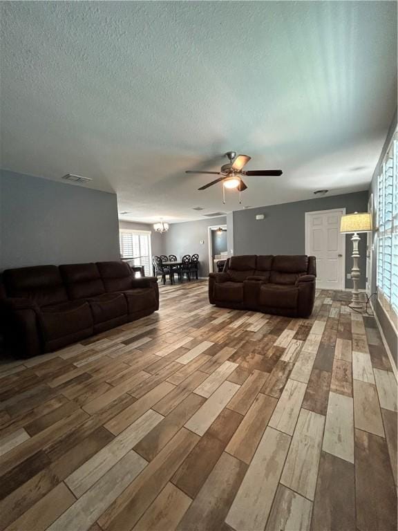 living room with ceiling fan, visible vents, a textured ceiling, and wood finished floors