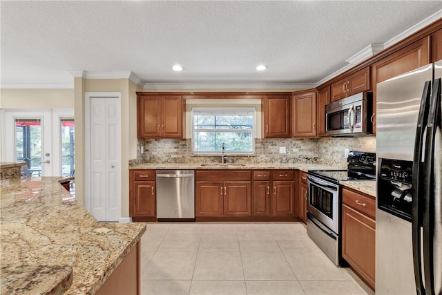 kitchen featuring sink, light stone counters, light tile patterned floors, ornamental molding, and appliances with stainless steel finishes