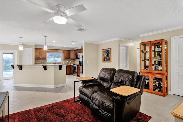 tiled living room featuring sink, ornamental molding, a healthy amount of sunlight, and ceiling fan