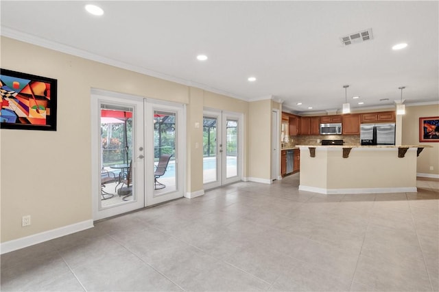 kitchen featuring french doors, crown molding, light stone counters, hanging light fixtures, and appliances with stainless steel finishes