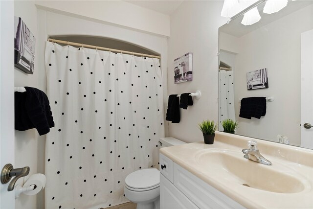 bathroom with curtained shower, vanity, and toilet