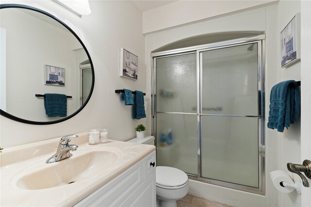 bathroom featuring toilet, an enclosed shower, vanity, and tile patterned flooring