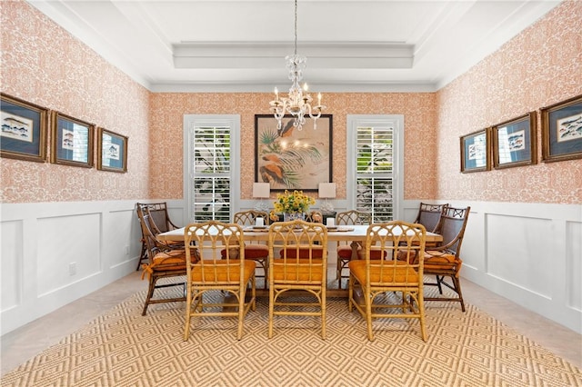 tiled dining room with an inviting chandelier, ornamental molding, and a tray ceiling