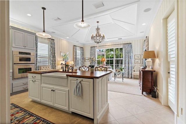 kitchen with a wealth of natural light, light colored carpet, stainless steel double oven, and decorative light fixtures