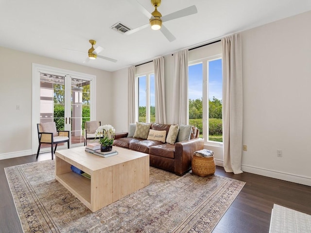 living area featuring dark wood-style floors, a ceiling fan, visible vents, and baseboards