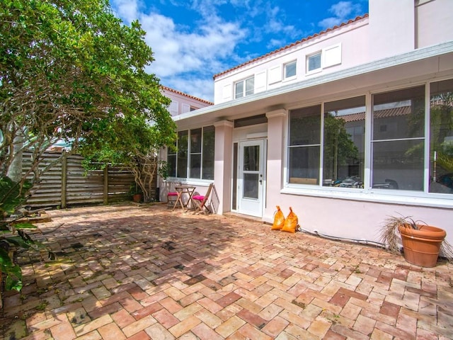 view of patio featuring a sunroom and fence