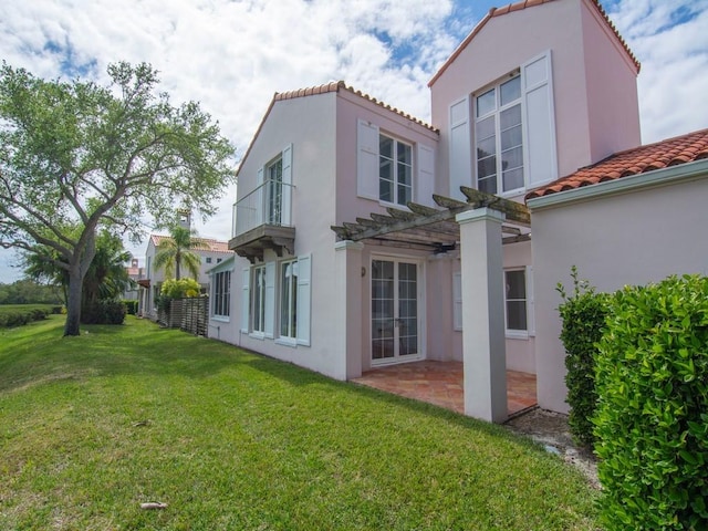 back of house featuring a patio, a tiled roof, a lawn, stucco siding, and a pergola