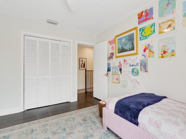 bedroom with baseboards, a closet, visible vents, and wood finished floors