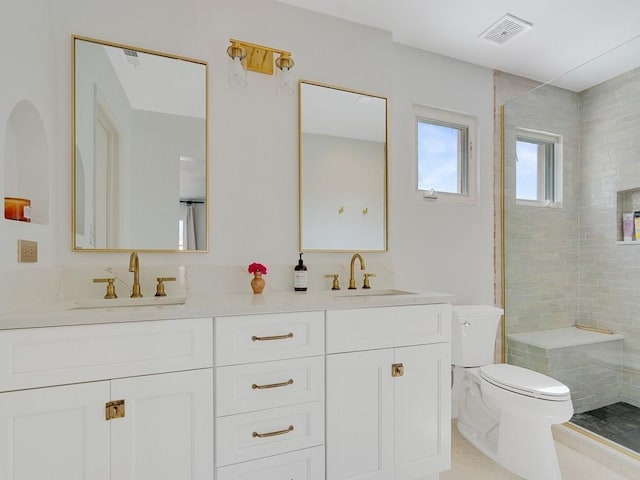 full bath featuring visible vents, a sink, a tile shower, and toilet