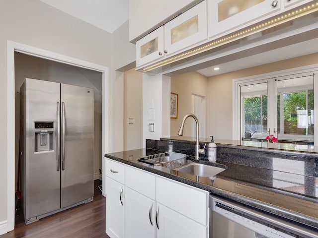 kitchen featuring white cabinets, appliances with stainless steel finishes, dark stone counters, and a sink