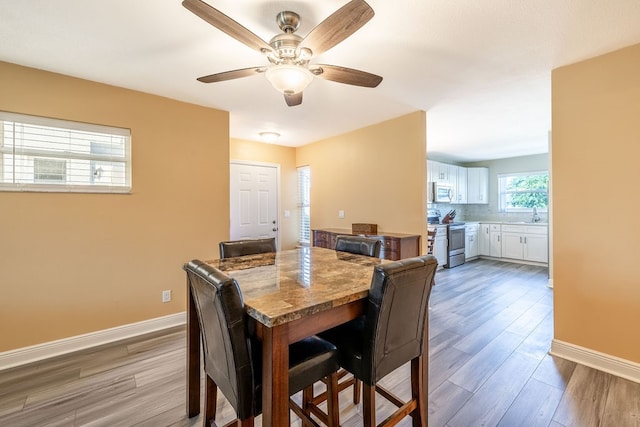 dining space with ceiling fan, sink, and light wood-type flooring